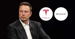 Elon Musk की एक तस्वीर जिसमें टेस्ला और स्पेसएक्स के लोगो दिखाई दे रहे हैं।
